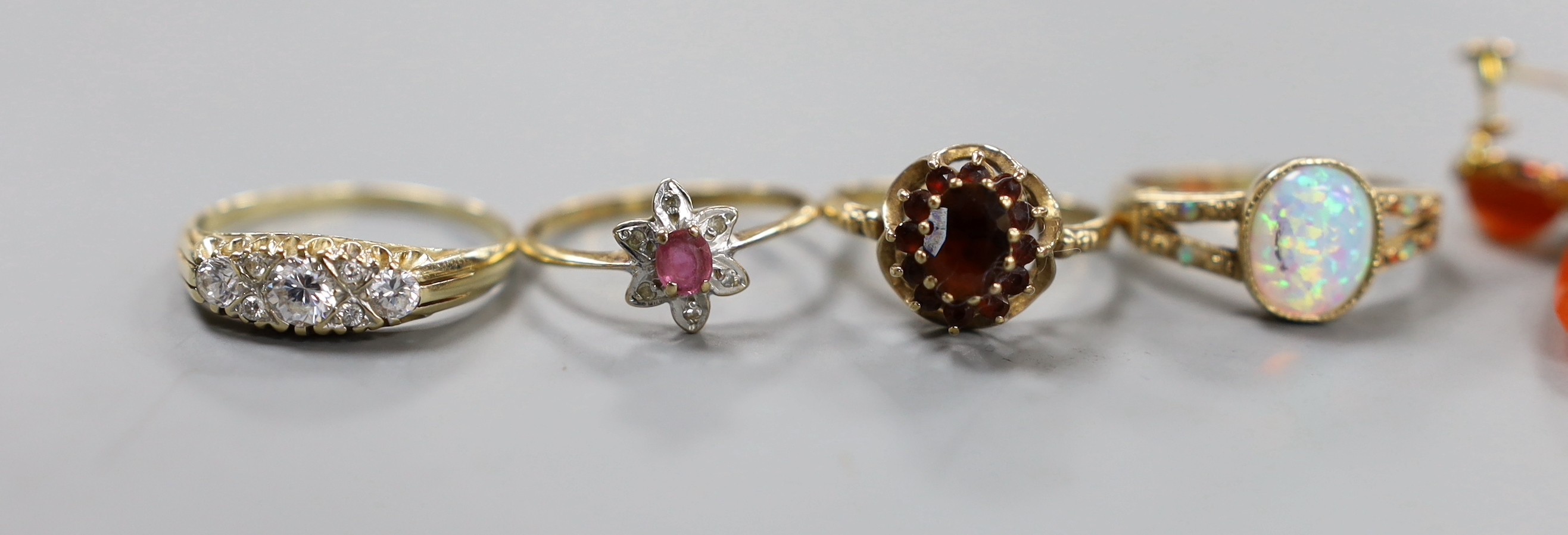 Eight assorted modern 9ct gold and gem set dress rings, a pair of 9ct and carnelian set drop earrings, gross weight 30.7 grams. and a yellow metal mounted shell pendant.